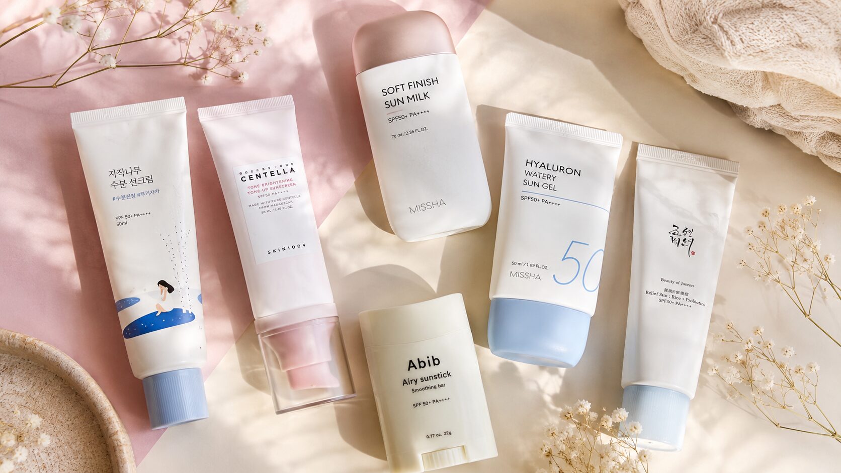 Flatlay of the best Korean sunscreens for every skin type on a pastel background