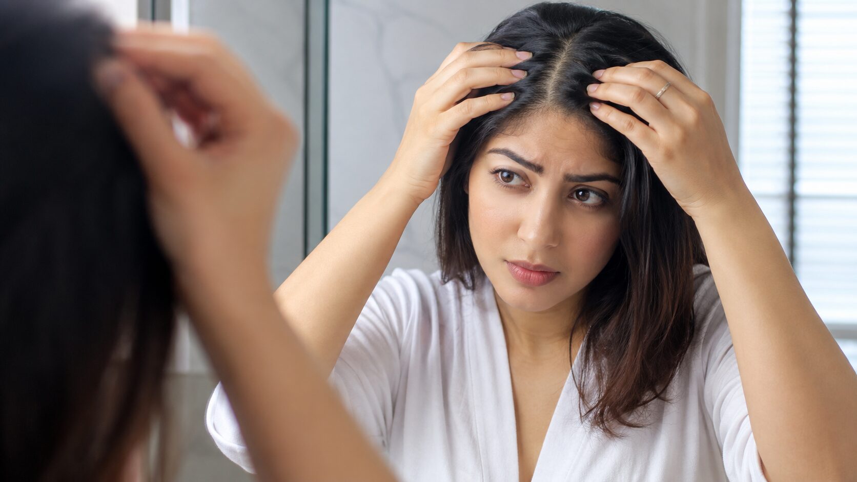 Woman checking thinning hair in mirror showing hair loss concern